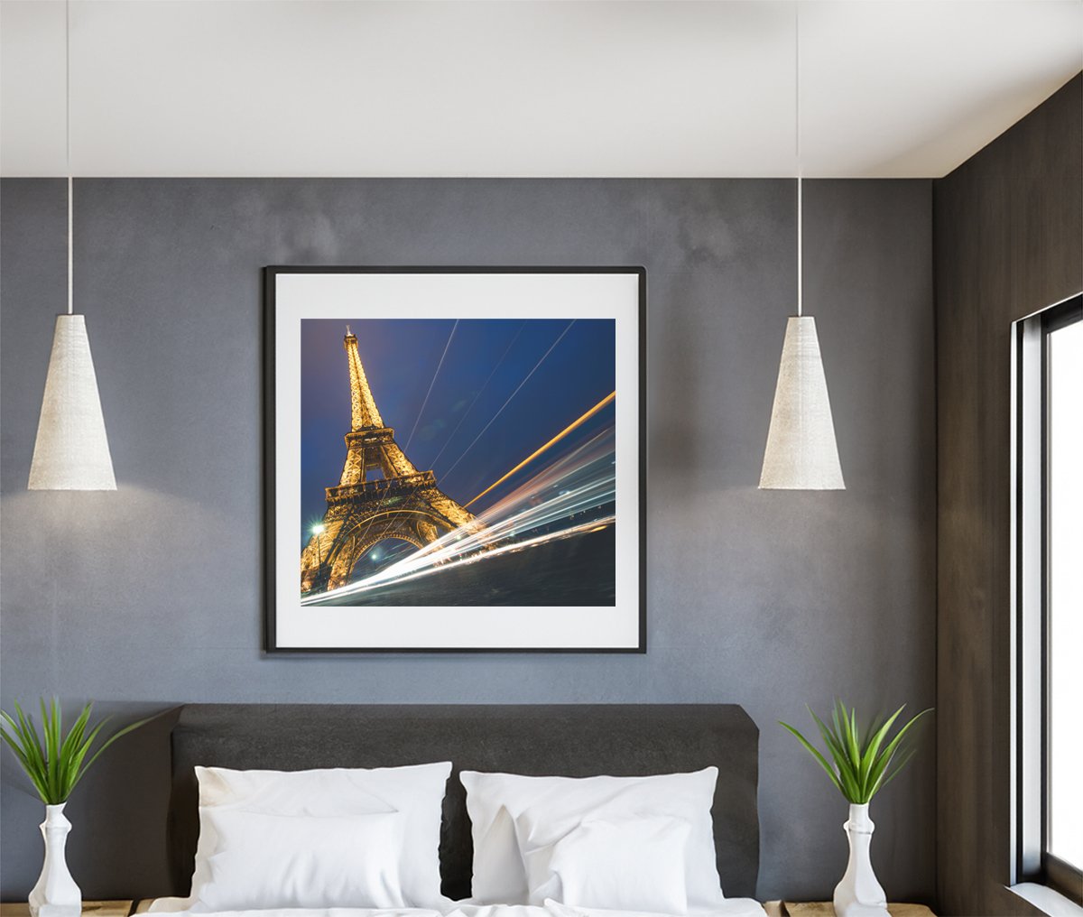 Night time view of the eiffel tower with light trails from passing vehicles.